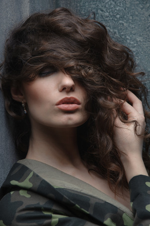 beautiful portrait of a curly girl in military uniform. girl with closed eyes waiting for the kissの写真素材