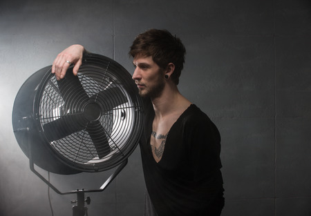 serious young man. was leaning against the fanの写真素材