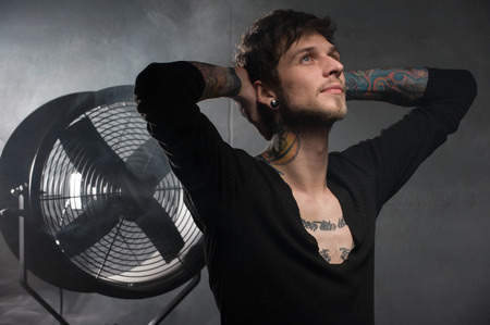 guy with the tattoos looks up with hope. with a dreamy gaze holds both his hands behind headの写真素材