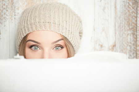 Close up portrait of beautiful hipster girl with nice hat, who is looking at the camera wonderingly while holding suitcase, only her eyes are visible, isolated on a white backgroundの写真素材