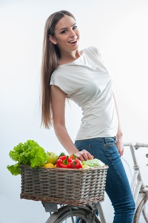 Full length portrait of pretty girl riding the bicycle on which there is a lot of healthy vegetation. isolated on white backgroundの写真素材