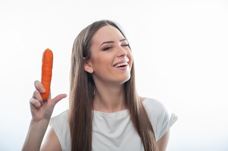 Waist up portrait of cheerful girl with healthy carrot. isolated on a white backgroundの写真素材