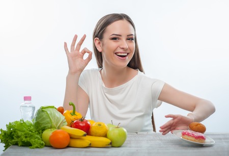 Beautiful woman is pushing the plate with donuts aside. Isolated on a white backgroundの写真素材