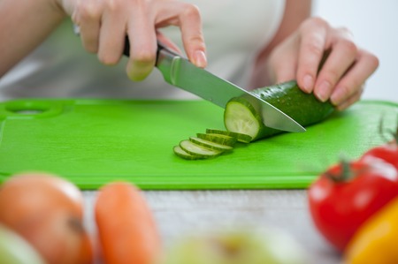 Close up of female hands cutting a cucumberの写真素材