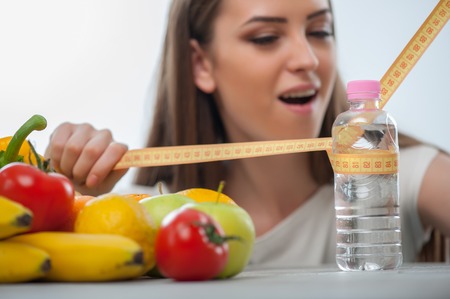 Pretty woman is measuring bottle of water with tape-line seriouslyの写真素材