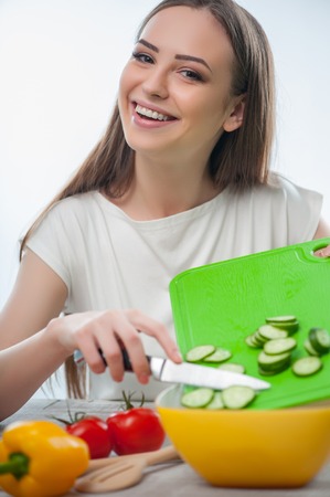 Cheerful girl is cooking healthy salad with pleasure. Isolated on a white backgroundの写真素材