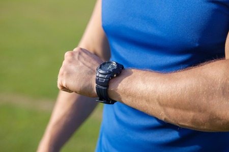 Close up of male torso. The man is raising his arm with watch to his abdomenの写真素材