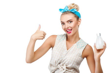 Attractive woman is holding bottle of fluid soap in her hand. She is showing her thumb up and smiling. Isolated on background and there is copy space in left sideの写真素材