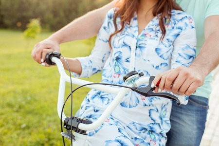 Close up of unrecognizable boyfriend and girlfriend cycling with enjoyment. Their hands are touching each others on handlebarの写真素材