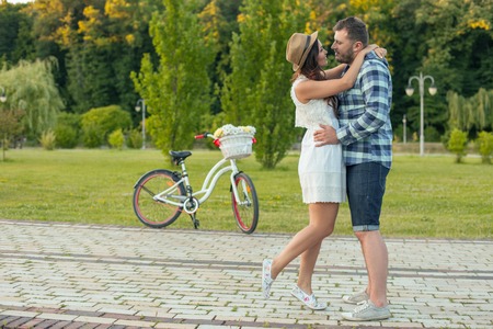 I love you. Beautiful loving couple is embracing and smiling. They are looking at each other with love. They are standing near the bicycle and there is copy space in left sideの写真素材
