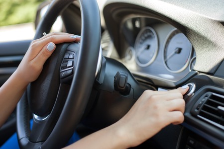 Close up of female arm starting her modern car. She is touching steering wheel