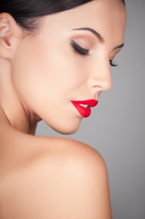 Attractive girl is showing her naked shoulder. She closed her eyes with passion. The lady is gently smiling. Isolated on backgroundの写真素材