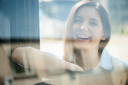 Beautiful woman is leaning on the handle of the bus and smiling. She is looking at the camera with joyの写真素材