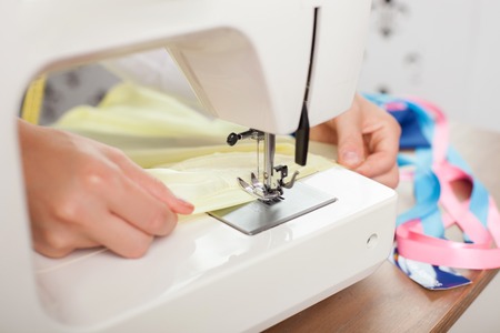 Close up of hands of clothes designer. The woman sews a cloth with the help of sewing machine