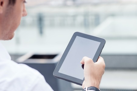 Close up of man using a tablet for his work. He is looking at the technology with concentrationの写真素材