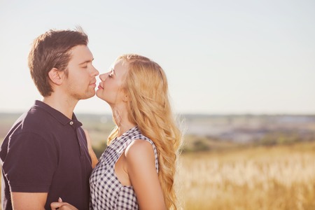 Pretty loving couple is standing and relaxing in the meadow. They are embracing with love and...