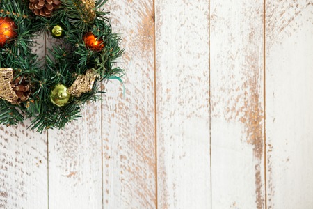 Christmas wreath of fir tree is hanging on white wall. There are many varicolored toys and cones on decoration. Copy space in right sideの写真素材
