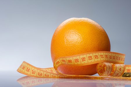 Close up of fresh round orange with tape-measure. Isolated on blue backgroundの写真素材
