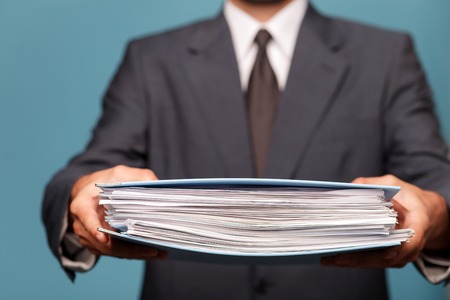 Close up of body of businessman holding a big folder of documents. The man is standing in suitの写真素材