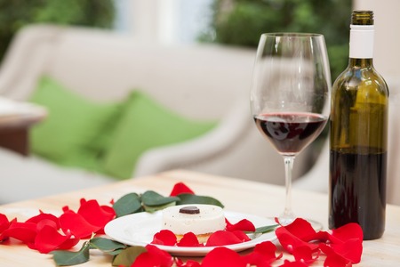 Close up of romantic diner on the table in restaurant. Red wine, petals and cake create this valentine atmosphereの写真素材
