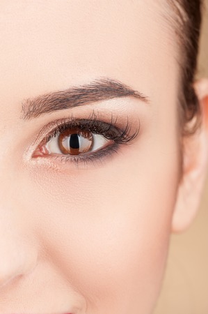 Close up of eye of cute young woman looking forward happily. She is receiving make-up treatmentの写真素材