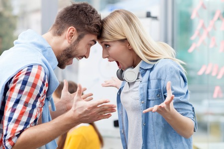 Cheerful creative team is celebrating the success of their project. The man and woman are looking at each other happily and gesturing. They are standing and laughingの写真素材