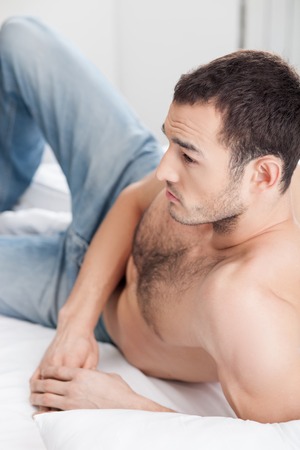 Handsome man is expressing his passion. He is lying in bed and looking forward with anticipation.の写真素材