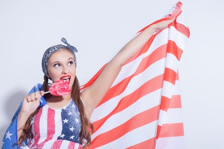 My country is freedom. Waist up portrait of cheerful young woman standing and holding usa flag. She...
