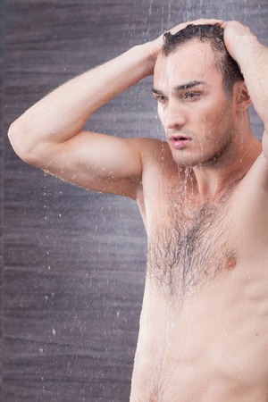 Portrait of cheerful man taking a shower. He is standing and relaxingの写真素材