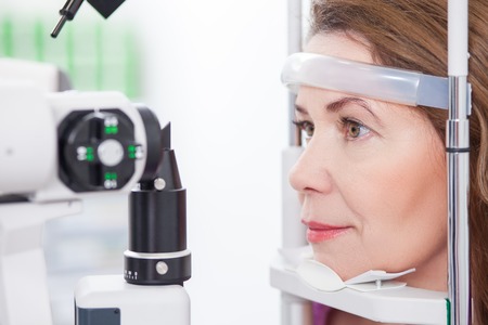 Cheerful woman is having eye examination at the slit lamp in optometrist lapの写真素材