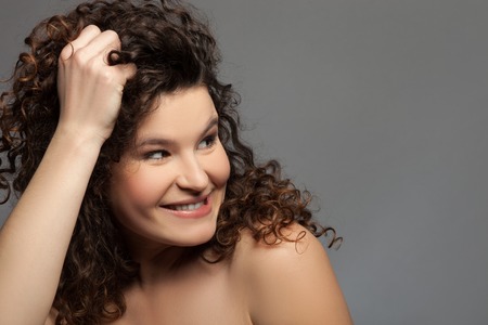 I am crazy about you.  Beautiful curly woman is looking aside with desire. She is touching her hair and smiling flirtingly. Isolated and copy space in right sideの写真素材