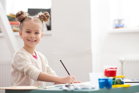 Talented small painter is creating a picture. The child is looking at the camera and laughingの写真素材