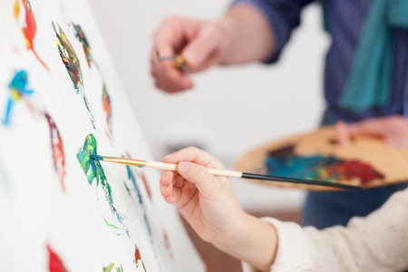 Close up of arms of grandfather and granddaughter painting togetherの写真素材