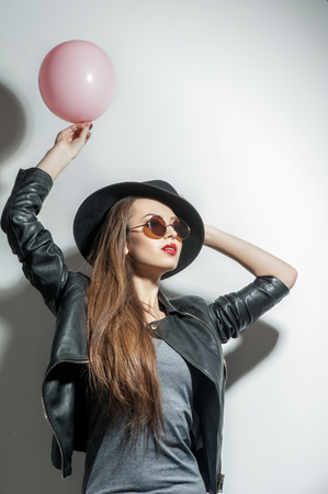 Beauty woman is holding a balloon. The lady is touching her hat and looking forward with passionの写真素材