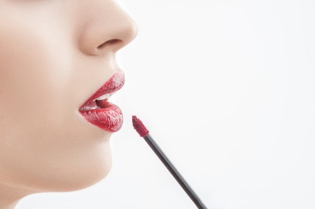 Close up of face of young sexy woman applying lip gloss. She is opening her mouth with temptation. Isolated and copy space in right sideの写真素材