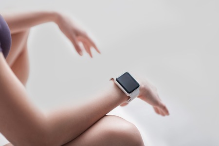 Close up of arms of gymnast woman sitting and resting. Focus on the smart watch on her wrist. Isolated and copy space in right sideの写真素材