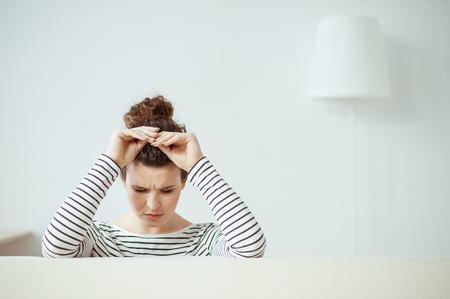 Beautiful girl is crying with sadness. She is raising arms to her head. Her eyes are closed with frustration. Copy space in right sideの写真素材