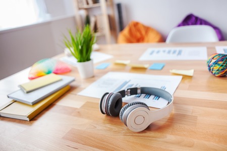 Close up of headphones, notepads and documents on the table in office. Focus on earphonesの写真素材