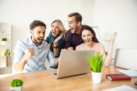 We have done it. Cheerful creative team is celebrating the great result of their work. They are gesturing and smilingの写真素材