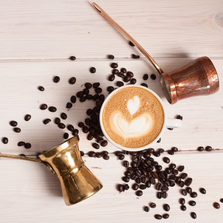 Top view close up of cup of latte around two pots and coffee beans on deskの写真素材