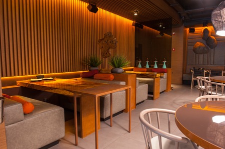 Wonderful interior of modern restaurant. Wooden tables and small couches create cozy atmosphereの写真素材