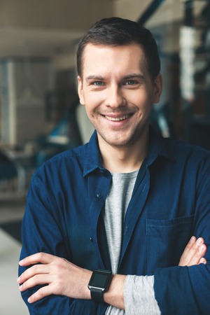 Portrait of attractive young man standing and smiling. He is looking at camera with happinessの写真素材
