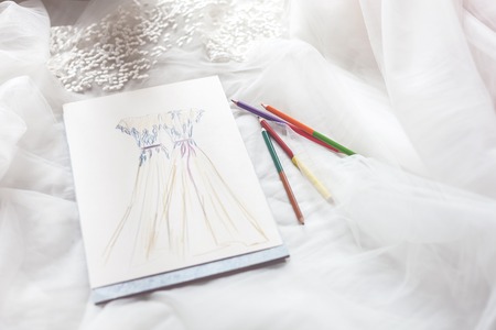 Close up of sketch of wedding dress near pencils on white clothの写真素材