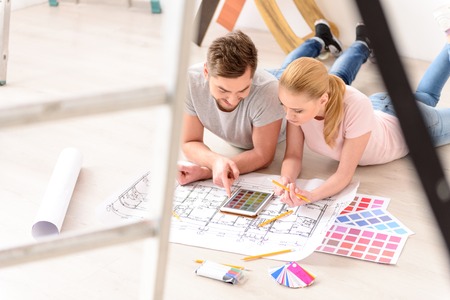 Lot of color options. Top view of young couple discussing selected color on tablet for repair in...
