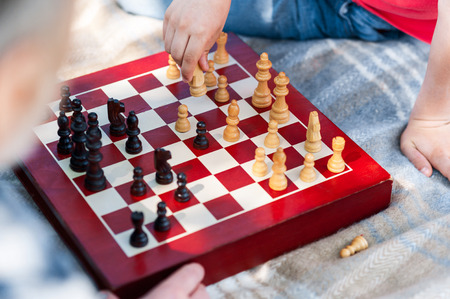 Close up of chess board on the blanket. Grandfather and boy are sitting and playing togetherの写真素材