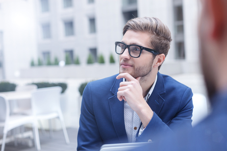 Handsome young businessman is planning new project with his colleague. He is looking forward dreamingly. Business partners are sitting in restaurantの写真素材