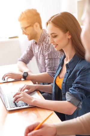 We make studying look easy. Smiling girl studing at her laptop with guy in background