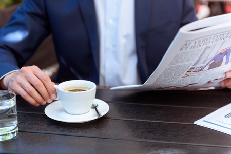 Close-up arm man coffee newspaper table restaurantの写真素材