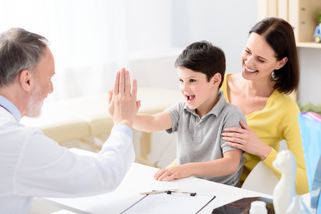 Smiling boy giving high five to handsome middle aged doctorの写真素材