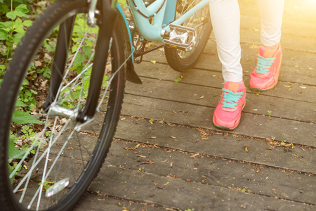 Close up of female legs walking in park. Young woman is riding a bicycleの写真素材
